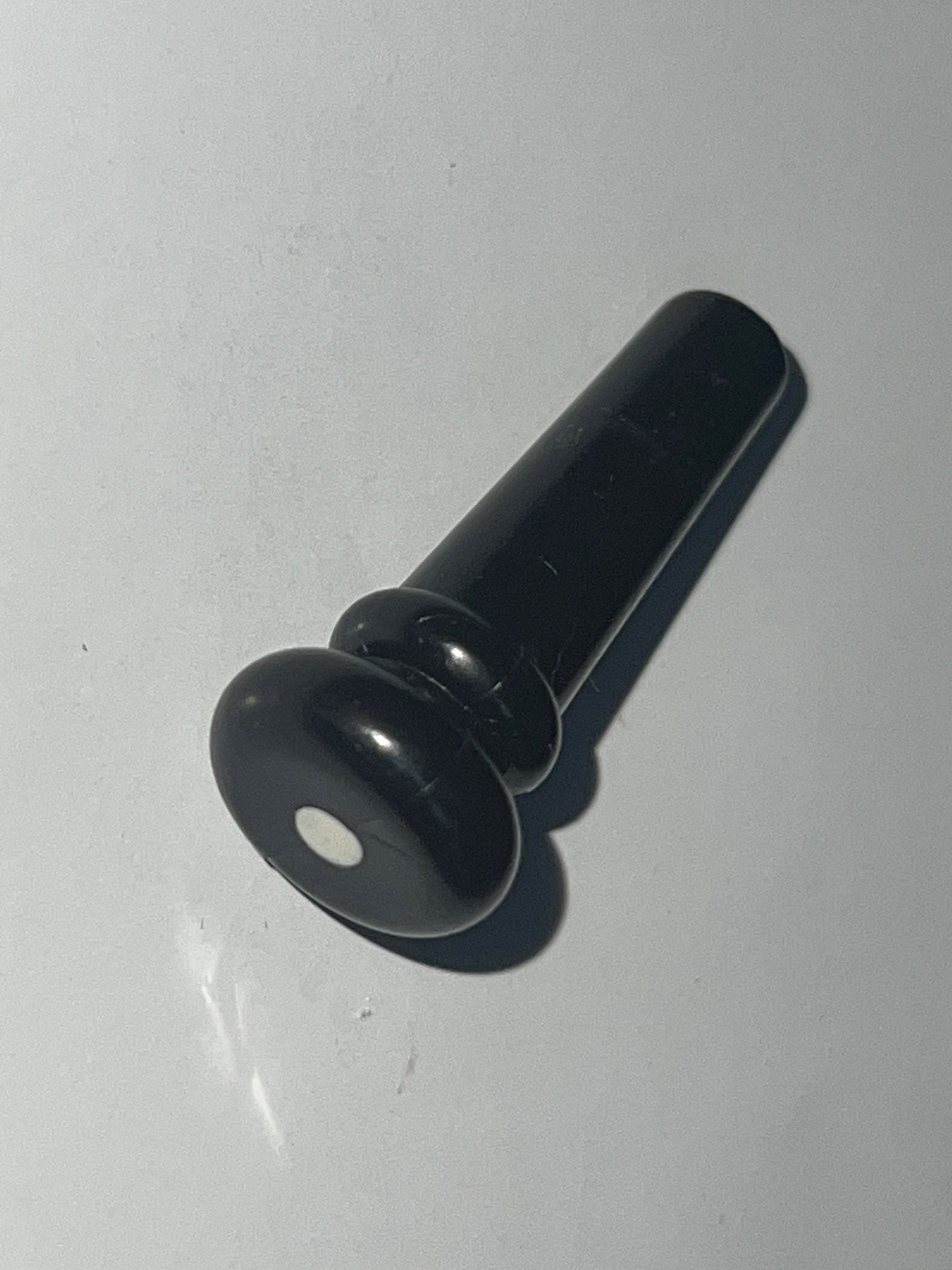 Black plastic guitar end pin button with white dot